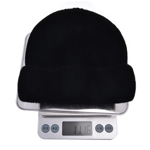 Detailed shot of a black winter knit beanie on a digital scale showing 111.6 grams weight