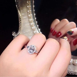Anillo halo ovalado con piedras laterales de pera en la mano con perlas finas