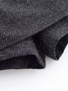 Close-up of premium black and gray tweed fabric texture on a fashion skirt suit set