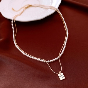 Dettaglio della collana a strati placcata oro 14K con catena di perle e ciondolo Good Luck
