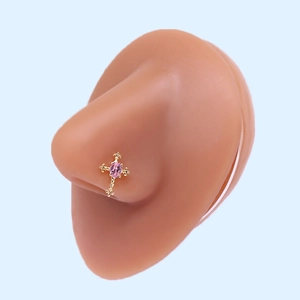Gold cross nose stud with pink oval zircon shown on a silicone model piercing