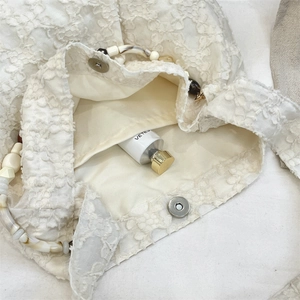 Vue détaillée de la poignée en perles et de la fermeture magnétique du sac en dentelle