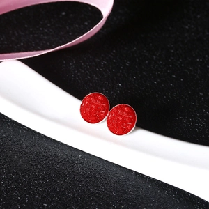 Macro view of round red crystal stud earrings with silver base on white ceramic prop