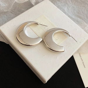 Close-up of chunky silver C-shape metal hoop earrings with high-polished mirror finish