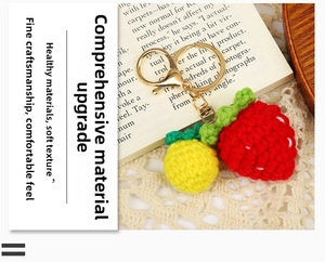 Close-up of hand-knitted strawberry and pineapple keychains with golden metal clasp