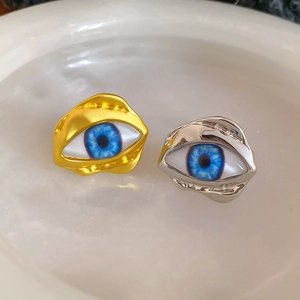 Detailansicht goldener und silberner Evil Eye Ringe mit realistischer blauer Iris-Textur
