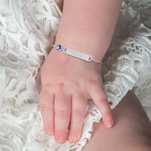 Close-up of baby silver bracelet with customizable nameplate and blue evil eye charm