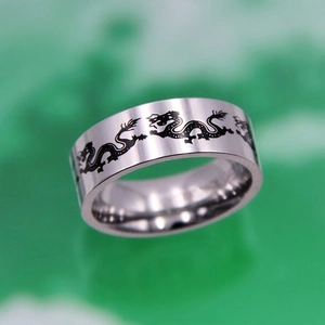Detailed view of silver titanium steel ring with black dragon totem on green background