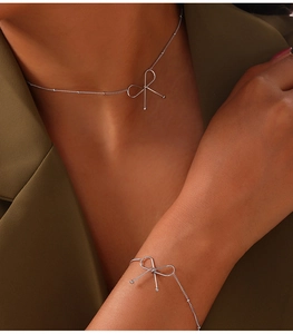 Minimalist silver bow pendant necklace and bracelet set displayed on a model