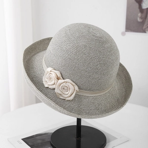 Détail d'un chapeau de paille élégant avec des roses en soie blanc cassé décoratives