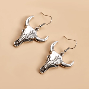 Vue macro de boucles d'oreilles tête de mort de taureau argentées au style punk bohème