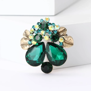 Detailed close-up of emerald crystal flower brooch with aurora rhinestones on gold base