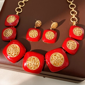 Primo piano di un set di gioielli vintage in smalto rosso con collana e orecchini dorati