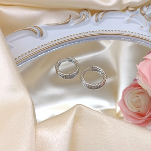 Detailed shot of silver textured hoop earrings on soft silk with floral accents
