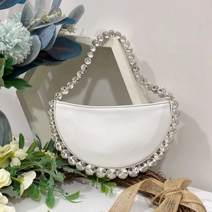 Close-up of a white crescent handbag featuring large crystal rhinestones on the edges