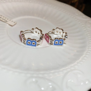 Detailed close-up of zircon letter B hoop earrings with pink and blue enamel finish