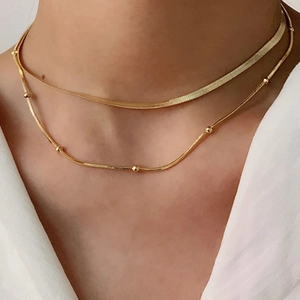 Close-up of double layered gold titanium necklace with flat snake chain and bead detail