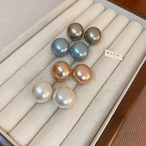Detail of round pearl earrings in white, champagne, grey, and blue on velvet tray