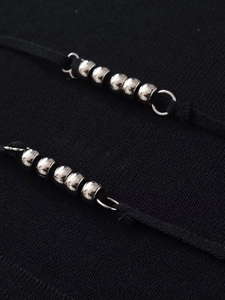 Close-up of silver metal beads on black knitted backless strap for women's top