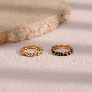 Detail of two gold-plated rings with double-row micro-set white and green crystals