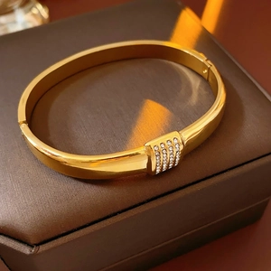 Gros plan d'un bracelet en acier titane doré avec strass blancs sur une boîte à bijoux