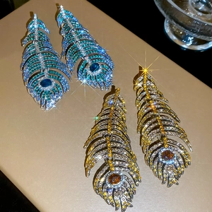 Close-up of luxury leaf feather earrings with blue and gold pavé crystals for women