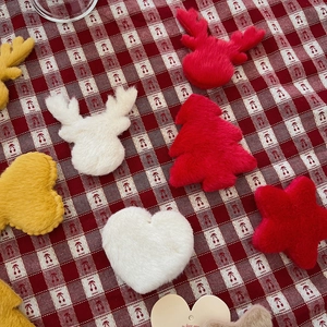 Close-up of fluffy Christmas tree and reindeer plush ornaments on a red checkered cloth