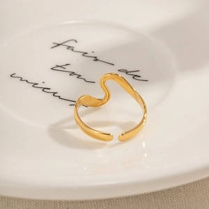Macro shot of gold irregular wave open ring on a white decorative porcelain plate