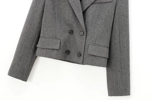 Detailed close-up of grey herringbone wool fabric and double-breasted buttons on the blazer