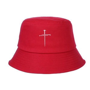 Gros plan sur un bob en coton rouge avec broderie croix blanche en forme de clous
