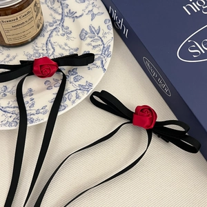 Detail of red fabric rose and black satin ribbon bow hair clip in a vintage style