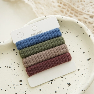 Detail of four ribbed elastic hair ties in retro colors on a white branded display card