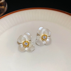 Macro shot of gold-plated flower earrings with pearl finish petals and zircon center