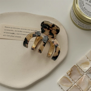 Detail of tortoise shell acetate hair claw clip with gold spring on a tray