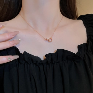 Detail of rose gold double interlocking rings necklace with sparkling zircon pavé on model