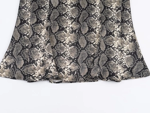 Detail of snake print midi skirt showing hemline stitching and fabric texture