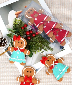 Detailed view of red and teal felt gingerbread man ornaments with holiday pine cones