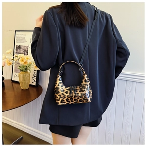 Close-up of leopard print crescent bag with glossy finish and adjustable strap