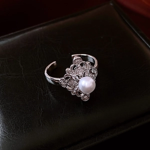Detailed macro view of an open floral ring with a white pearl and sparkling zircons