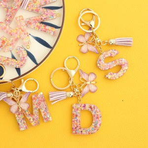 Pink floral resin alphabet keychain with purple butterfly and tassel charms on gold ring