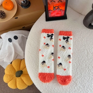 Detail of coral fleece Halloween socks with pumpkin and ghost patterns on plush background