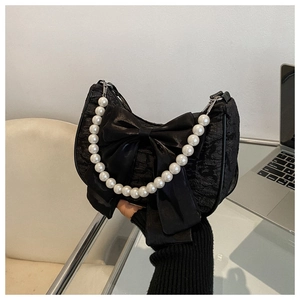Detail of black pleated fabric bag with large satin bow and pearl bead handle