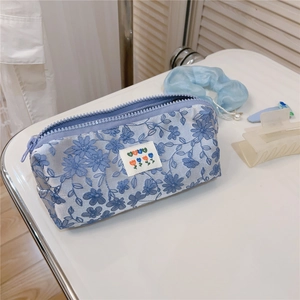 Close-up of floral embroidered light blue stationery pouch with purple zipper closure