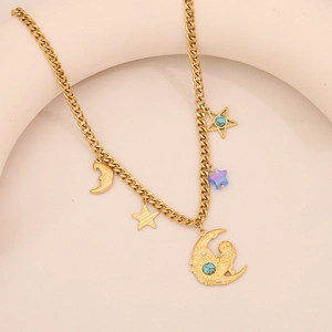 Macro detail of gold necklace with star, moon and owl pendants on a minimal beige setup