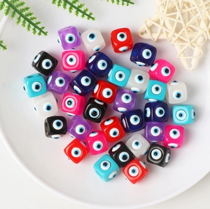 Close-up of colorful resin square evil eye beads for DIY jewelry making in a white bowl