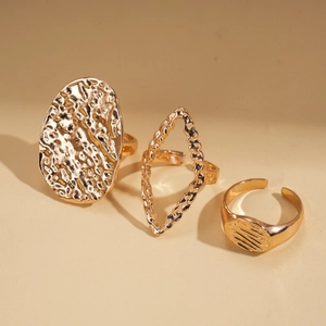 Détail de 3 bagues dorées en métal aux textures géométriques avec un design ouvert réglable
