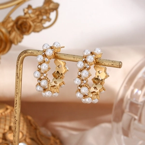 Macro detail of gold-plated hoop earrings featuring inlaid pearls and sparkling crystals