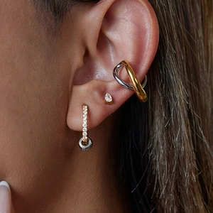 Detail of mixed metal hoop earring with crystal pendant on model's ear lobe