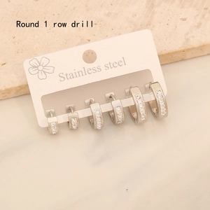 Three pairs of silver stainless steel hoop earrings with round rhinestones on a display card