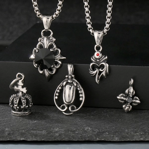 Close-up of vintage crown and cross pendants with black gemstones on textured surface